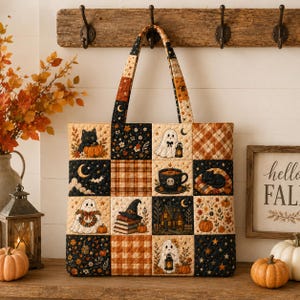May include: A quilted tote bag featuring a patchwork design with Halloween-themed illustrations including ghosts, black cats, pumpkins, a witch hat on books, a haunted house, and a cup of coffee, all set against a black, orange, and cream color palette.