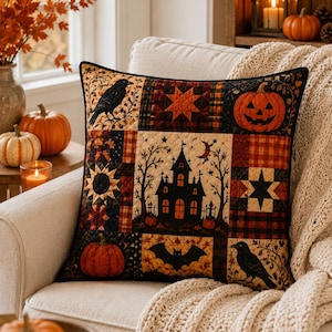 May include: A square decorative throw pillow featuring a patchwork quilt design with Halloween motifs. The pattern includes a black haunted house, a jack-o'-lantern, black crows, a bat, and geometric star shapes in shades of orange, black, and brown.