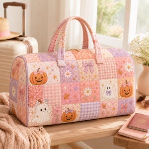 May include: A quilted duffel bag featuring a patchwork design in shades of pink, lavender, and white. The pattern includes illustrations of smiling jack-o'-lanterns with bows, white ghosts, daisies, bows, and small stars on a checkered background.