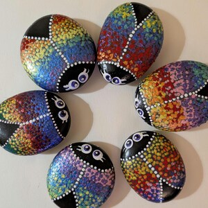 Lieveheersbeestje schommelt. Handbeschilderde middelgrote stenen.