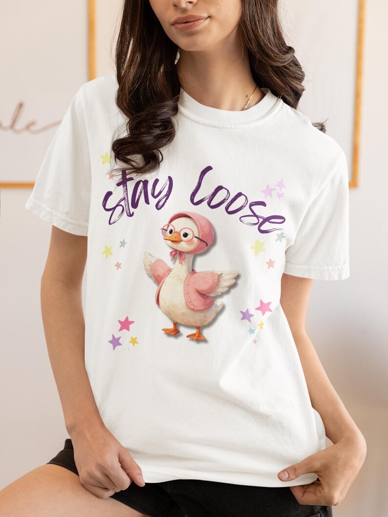 A woman wearing a white t-shirt with a cartoon image of a duck and the text "Stay Loose" printed on it.