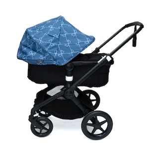 May include: A black stroller with a blue canopy featuring a white pattern. The stroller has four black wheels and a black frame. The canopy is extended, and the handle is angled upwards.
