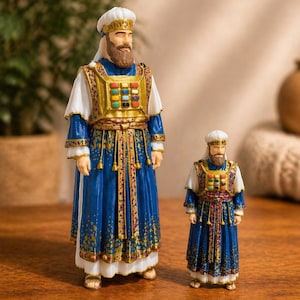 May include: Two detailed figurines of religious figures. The figures are dressed in blue and white robes with gold accents. The larger figure stands approximately 15 cm tall, while the smaller one is about 10 cm tall. Both have beards and head coverings.