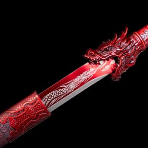 Puede incluir: Una espada decorativa roja con una empuñadura de cabeza de dragón y una hoja con un diseño de dragón blanco. La vaina de la espada también es roja y tiene un patrón ornamentado. El fondo es negro.