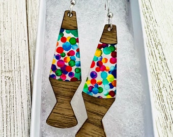 May include: A pair of colorful lava lamp earrings with a wood base. The earrings are in a white box.