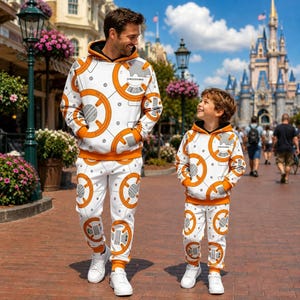 May include: Matching white hoodies and sweatpants sets featuring an orange and grey circular geometric pattern inspired by BB-8. The hoodies include a hood and long sleeves, while the sweatpants have an elastic waistband and cuffs.