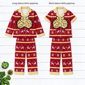 May include: Two sets of red pajamas featuring a repeating white pattern of reindeer and snowflakes. The left set has long sleeves, and the right set has short sleeves. Both feature a beige collar and a graphic of two beige, textured shapes.