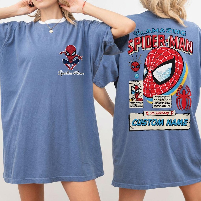 K&ouml;nnte beinhalten: Blaues T-Shirt mit Spider-Man-Grafiken. Die Vorderseite zeigt ein kleines Spider-Man-Logo und Text. Die R&uuml;ckseite zeigt ein gro&szlig;es Spider-Man-Maskendesign mit dem Text "the AMAZING SPIDER-MAN" und Platz f&uuml;r einen individuellen Namen.