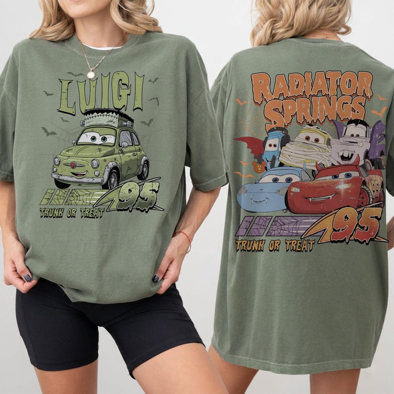 May include: An olive green t-shirt with a cartoon car design, the name "Luigi", and the text "Trunk or Treat 95" on the front. The back of the shirt shows "Radiator Springs" and Halloween-themed car characters.