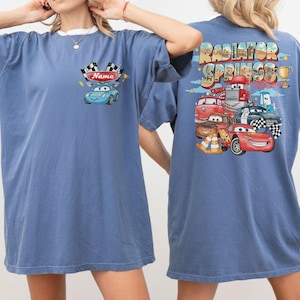 Puede incluir: Camiseta azul con un dise&ntilde;o de coche de dibujos animados en la parte delantera, incluyendo el texto "Name". La parte trasera de la camiseta muestra el texto "Radiator Springs" y varios personajes de coches de dibujos animados y un trofeo.