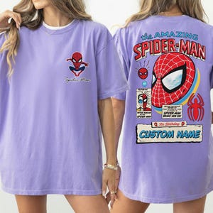 K&ouml;nnte beinhalten: Ein helllila T-Shirt mit Spider-Man-Grafiken auf der Vorder- und R&uuml;ckseite. Das R&uuml;ckendesign enth&auml;lt den Text "the AMAZING SPIDER-MAN", eine Spider-Man-Maske und Platz f&uuml;r einen individuellen Namen. Auf der Vorderseite befindet sich das Spider-Man-Logo.