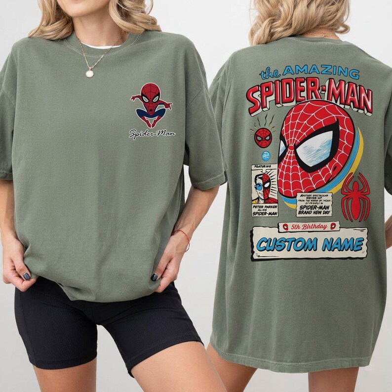 K&ouml;nnte beinhalten: Olivgr&uuml;nes T-Shirt mit Spider-Man-Grafiken auf der Vorder- und R&uuml;ckseite. Die Vorderseite zeigt ein kleines Spider-Man-Logo und Text. Die R&uuml;ckseite zeigt ein gro&szlig;es Spider-Man-Comic-Design mit dem Text "the AMAZING SPIDER-MAN".