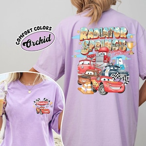 Puede incluir: Una camiseta de color lila claro con un gr&aacute;fico de personajes de dibujos animados y el texto "Radiator Springs" y "Lightning McQueen". La camiseta tambi&eacute;n tiene el texto "Comfort Colors Orchid".