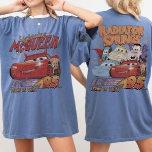 May include: Blue t-shirt with a Lightning McQueen graphic on the front and Radiator Springs on the back. The front design includes the text "Lightning McQueen" and "95", while the back design includes "Radiator Springs" and "Trunk or Treat".