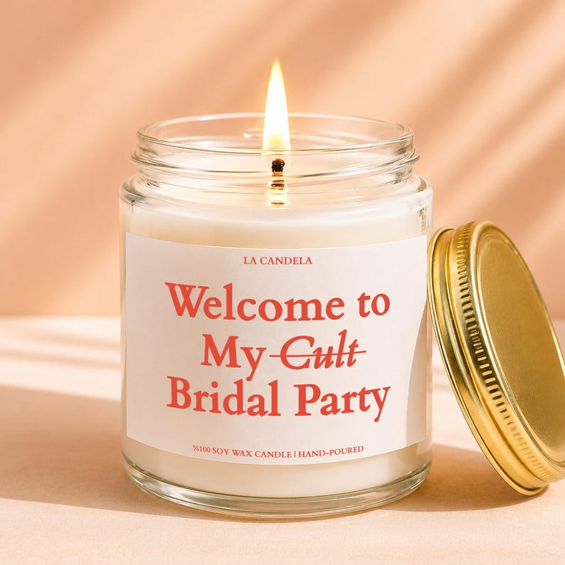 A lit candle in a glass jar with a label that says "Welcome to My Cult Bridal Party" and "100% Soy Wax Candle Hand-Poured".