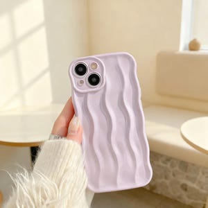 Könnte beinhalten: Eine weiße Keramik-Tasse mit schwarzem Henkel und dem Text "But First, Coffee" in fetter, schwarzer Schrift. Die Tasse steht vor einem verschwommenen Hintergrund, der eine gemütliche Umgebung suggeriert.