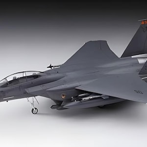 Puede incluir: Maqueta gris de avión F-15 Eagle. El modelo presenta detalles como cabina, alas y aletas de cola. Las aletas de cola muestran las letras "MO" y el número "207". El modelo está sobre un fondo blanco.