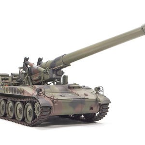 Puede incluir: Un tanque militar con un cañón largo, pintado en colores de camuflaje verde, marrón y beige. El tanque tiene un chasis de orugas y está sobre un fondo blanco. El cañón está inclinado hacia arriba.