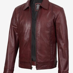Könnte beinhalten: Burgunderfarbene Lederjacke mit Kragen und Reißverschluss vorne. Die Jacke hat ein klassisches Design mit taillierter Passform, schwarzem Innenfutter und einem kleinen Etikett. Die Jacke hat zwei Seitentaschen.