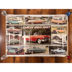 May include: A poster featuring a collage of classic Chevy cars from 1955-1957. The cars are in various colors, including red, blue, green, and orange. The poster has a vintage aesthetic and is displayed on a wooden surface.