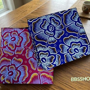 May include: Two square fabric pouches featuring a bold floral pattern. One pouch has a deep magenta background with blue and yellow flower outlines, while the other has a vibrant blue background with white and brown floral motifs. Text reads BBSSHOP.