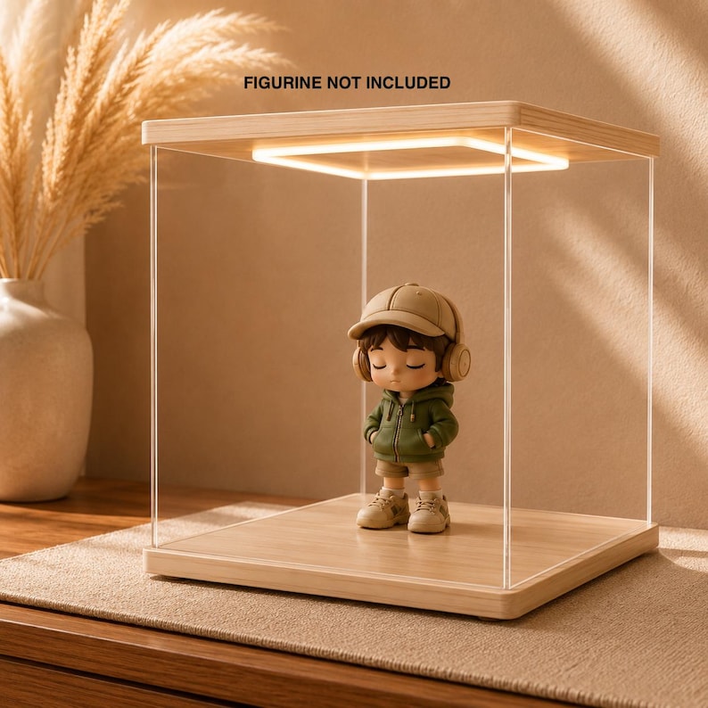 May include: A square display case with a light-colored wood base and top, featuring clear acrylic sides and an integrated square LED light on the underside of the top panel. The text FIGURINE NOT INCLUDED is printed above the display case.