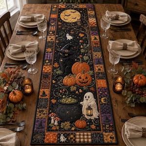 May include: A rectangular Halloween-themed table runner featuring a black background with a central design of a black cat, pumpkins, a cauldron, and a ghost. The border includes orange, purple, and black patchwork squares with spiderweb patterns.