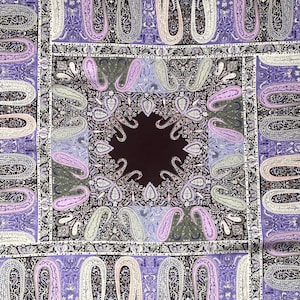 May include: A square textile featuring a paisley pattern in shades of purple, lavender, and white. The design includes a central dark brown square surrounded by intricate floral and teardrop motifs. The overall aesthetic is ornate and detailed.