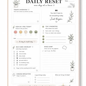 May include: A white Daily Reset planner with sections for intentions, mood, priorities, self-care, and reflection. The planner includes text and illustrations of plants and a candle. The phrase "Just begin" is featured.