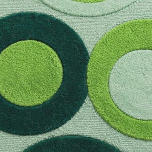 Op de afbeelding: Een getextureerd tapijt met een herhalend patroon van grote cirkels in verschillende tinten groen. Het ontwerp bevat donker bosgroene, levendig limoengroene en zachte mintgroene cirkelvormen tegen een lichtgroene achtergrond.