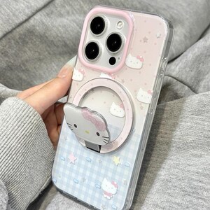May include: Clear phone case with a pink and blue design featuring Hello Kitty characters and stars. The case has a built-in ring holder with a Hello Kitty face. The text "Y2kXCases" is visible at the top.