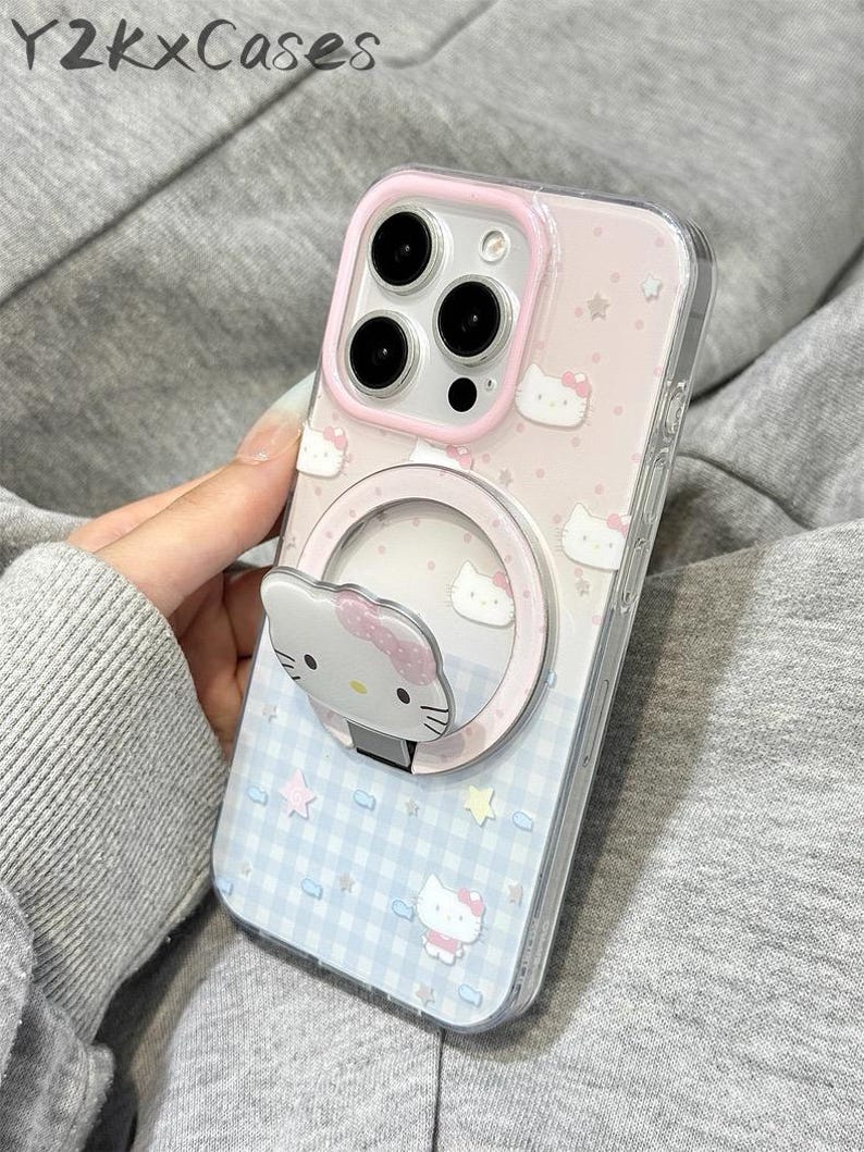 May include: Clear phone case with a pink and blue design featuring Hello Kitty characters and stars. The case has a built-in ring holder with a Hello Kitty face. The text "Y2kXCases" is visible at the top.