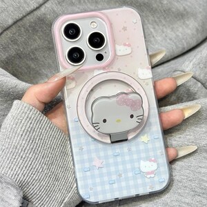 May include: Clear phone case with a pink and blue Hello Kitty design. The case features a pink border around the camera and a matching ring holder with a Hello Kitty face. The background has a pattern of stars, bows, and a gingham design. The text "Y2kxCases" is at the top.