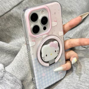 May include: Clear phone case with a pink and blue design featuring Hello Kitty characters. The case has a pink ring holder with a Hello Kitty face. The phone case has the text "Y2kXCases" at the top.