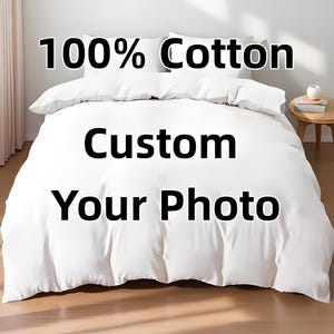 Könnte beinhalten: Ein weißes Bettwäsche-Set mit dem Text "100% Cotton" und "Custom Your Photo" in Schwarz. Die Bettwäsche umfasst einen Bettbezug und Kissen, alles in einem knackigen, sauberen Weiß. Das Set wird auf einem Bett präsentiert, was auf Wohnkultur und personalisierte Artikel hindeutet.