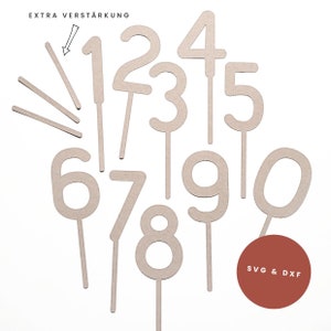 May include: A collection of wooden number cake toppers, ranging from zero to nine, with attached sticks for insertion. Includes extra reinforcement sticks. The text "EXTRA VERSTÄRKUNG" is visible at the top. A red circle with the text "SVG & DXF" is in the bottom right.