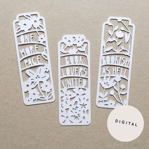 May include: Three white, laser-cut paper bookmarks with floral designs and text. The bookmarks read "ONE MORE PAGE", "BOOK LOVERS UNITED", and "BOOKISH AS HELL". A digital graphic is in the lower right corner. The bookmarks are on a tan background.