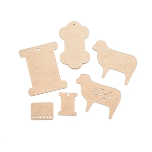 May include: A collection of unfinished wooden craft shapes, including two sheep, two spools, a bone-shaped tag, and a small rectangular piece with holes. These shapes are ideal for DIY projects and crafting.