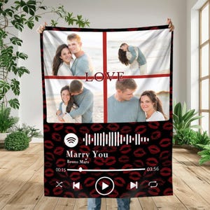 Pode incluir: Uma manta personalizada com quatro fotos de um casal, com a palavra "LOVE" em vermelho. A parte inferior tem um fundo preto com marcas de beijos de batom vermelho e um gráfico de reprodutor de música com a música "Marry You" de Bruno Mars.