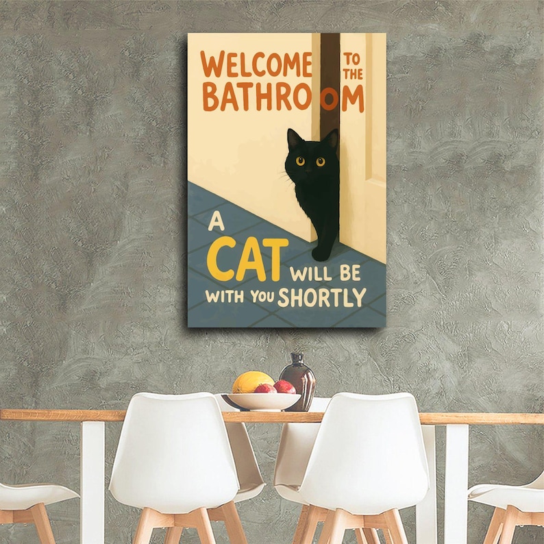 May include: A rectangular canvas print with the text "WELCOME TO THE BATHROOM" and "A CAT WILL BE WITH YOU SHORTLY." A black cat with yellow eyes peeks from behind a door. The background is a light beige and blue.
