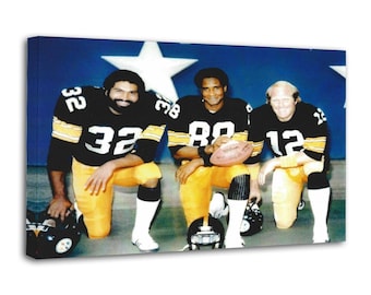 May include: A framed canvas print showing three American football players kneeling. They wear black and gold team uniforms with white numbers and stripes. One player holds a football. The background is blue with white stars.