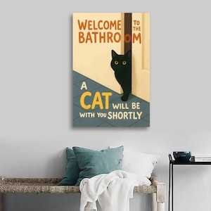 May include: A rectangular wall art print with the text "WELCOME TO THE BATHROOM" in orange and "A CAT WILL BE WITH YOU SHORTLY" in yellow and white. A black cat with yellow eyes peeks from behind a white door.