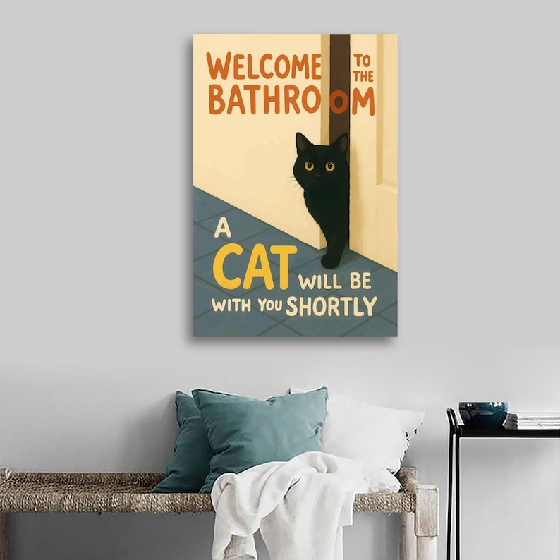 May include: A rectangular wall art print with the text "WELCOME TO THE BATHROOM" in orange and "A CAT WILL BE WITH YOU SHORTLY" in yellow and white. A black cat with yellow eyes peeks from behind a white door.