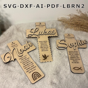 May include: Three wooden crosses with names and inscriptions. The crosses are light brown with laser-cut details. One cross has the name "Noah" and a rainbow. Another has "Lukas" and a dove. The third has "Sophie" and a fish symbol.
