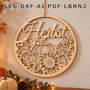 Könnte beinhalten: Ein kreisförmiger Wandbehang aus Holz mit dem lasergeschnittenen Schriftzug "Herbst" über einem detaillierten Motiv aus Kürbissen, einer Sonnenblume und Herbstblättern. Oben am Rahmen steht "SVG DXF AI PDF LBRN2" und eine Aufhängeschnur.