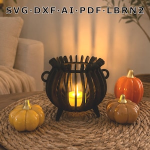 May include: A black wooden cauldron-shaped candle holder with vertical slats and two side handles, containing a glowing yellow LED candle. The text SVG, DXF, AI, PDF, LBRN2 is displayed above. Three small ceramic pumpkins in orange, yellow, and tan sit nearby.