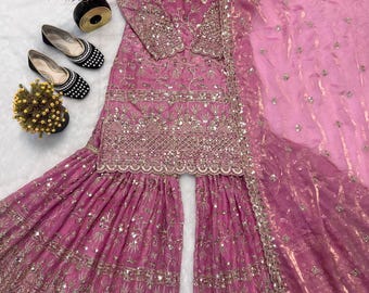 Op de afbeelding: Een mauve driedelige outfit bestaande uit een tuniek met lange mouwen en een wijde broek, beide versierd met ingewikkeld zilver borduurwerk en spiegelwerk. Een bijpassende transparante mauve dupatta met zilveren accenten maakt de set compleet.