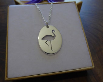 May include: A silver necklace with an oval pendant featuring a cut-out silhouette of a flamingo.
