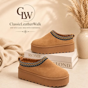 May include: A pair of tan suede platform slip-on shoes featuring a thick, notched rubber sole and a decorative black, white, and yellow woven trim around the collar. The interior is lined with brown faux fur, and a small pull tab is on the heel.