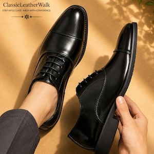 May include: A pair of black leather oxford shoes with a cap toe design and black laces. The shoes feature a smooth finish and a low heel. The text GW ClassicLeatherWalk STEP INTO CLASS. WALK WITH CONFIDENCE. is visible in the upper left corner.